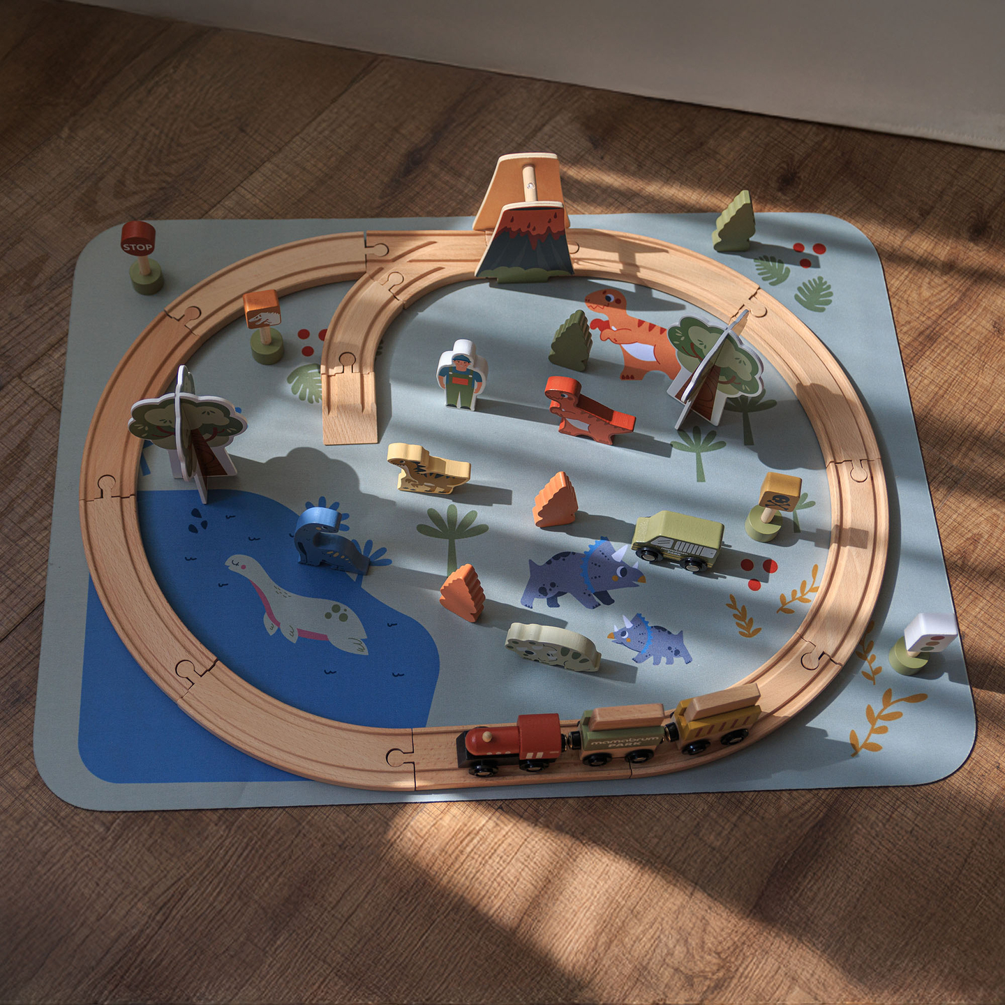 Trenuleț din lemn Dino Park cu covoraș antiderapant - dinozauri, tren, șine, vulcan, clopot